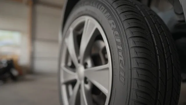 Lateral de um pneu de carro montado na roda, com as letras em relevo.